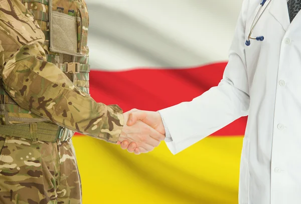 Military man in uniform and doctor shaking hands with national flag on background - South Ossetia — Stok fotoğraf