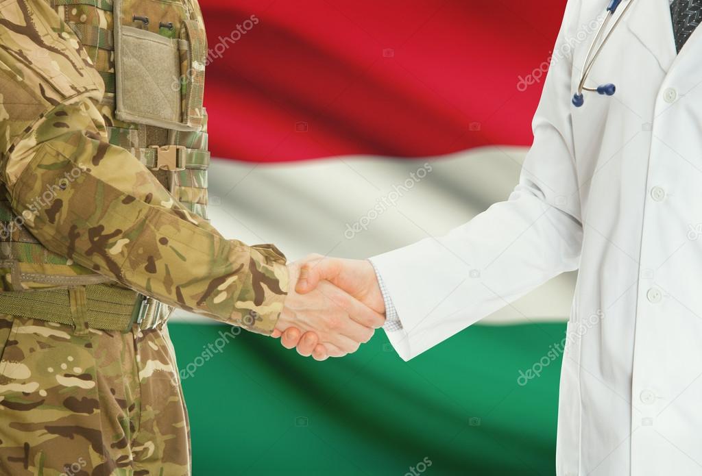 Military man in uniform and doctor shaking hands with national flag on background - Hungary