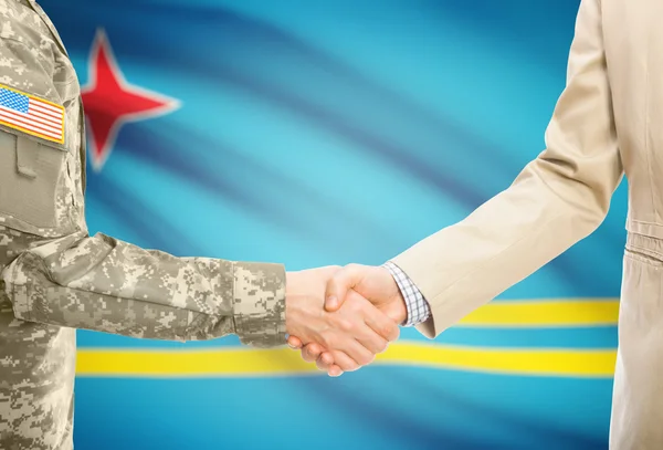 USA military man in uniform and civil man in suit shaking hands with national flag on background - Aruba — стокове фото