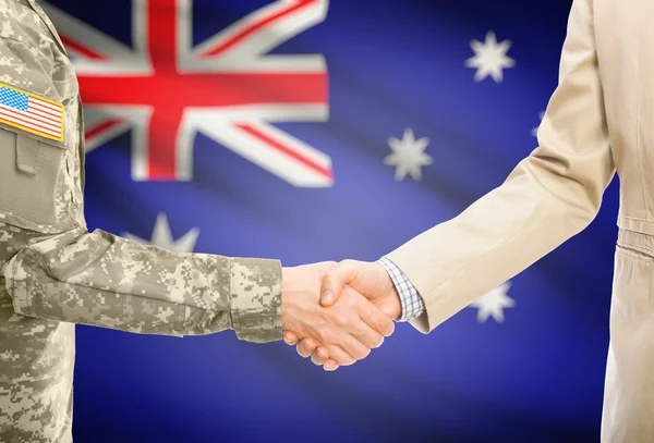 USA military man in uniform and civil man in suit shaking hands with national flag on background - Australia — Stock Fotó