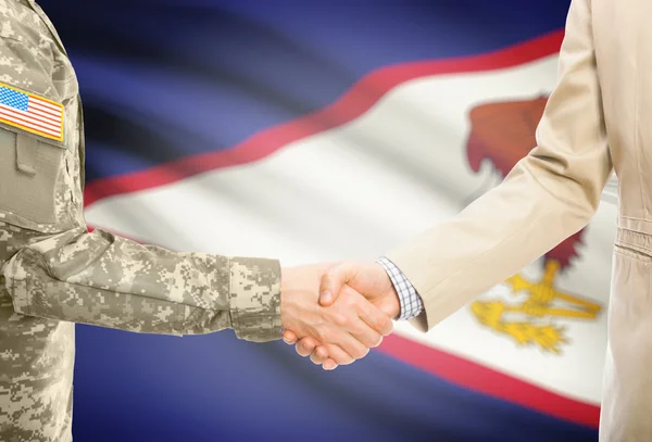 USA military man in uniform and civil man in suit shaking hands with national flag on background - American Samoa — Stockfoto
