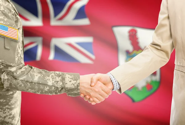 USA military man in uniform and civil man in suit shaking hands with national flag on background - Bermuda — Foto de Stock
