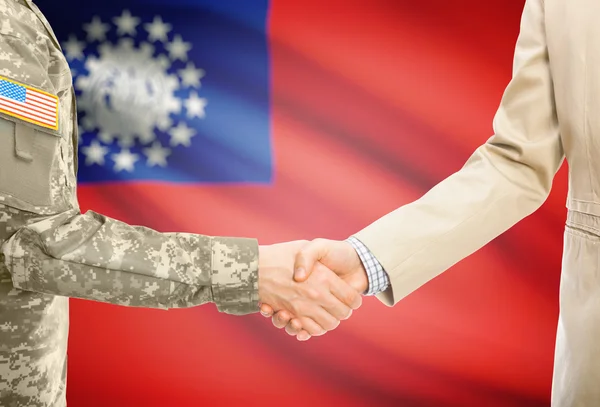 USA military man in uniform and civil man in suit shaking hands with national flag on background - Burma — Stock Fotó