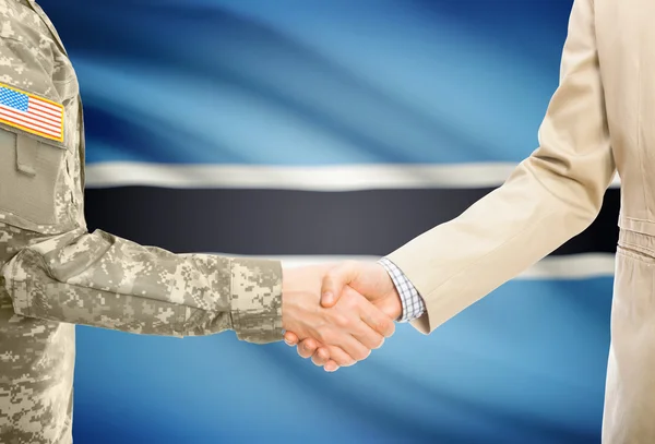 USA military man in uniform and civil man in suit shaking hands with national flag on background - Botswana — Stock fotografie