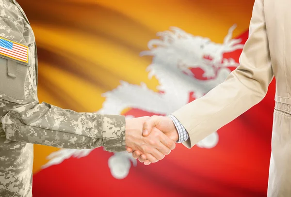 USA military man in uniform and civil man in suit shaking hands with national flag on background - Bhutan — стокове фото