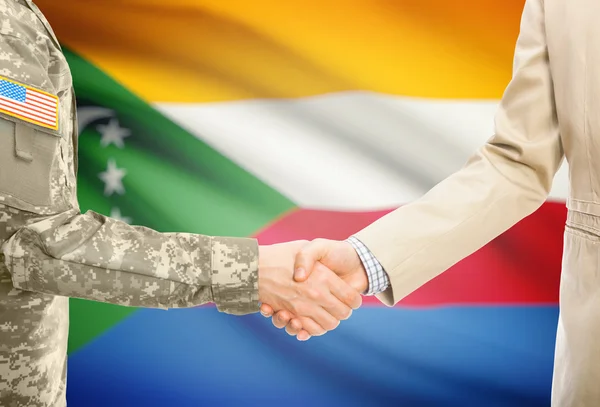 США военный человек в военной форме и гражданской мужчина в костюме, рукопожатие с национальным флагом на фоне - Коморские острова — стоковое фото