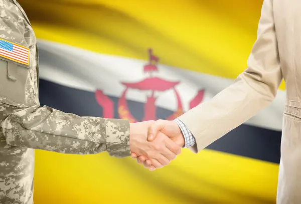 USA military man in uniform and civil man in suit shaking hands with national flag on background - Brunei — Zdjęcie stockowe