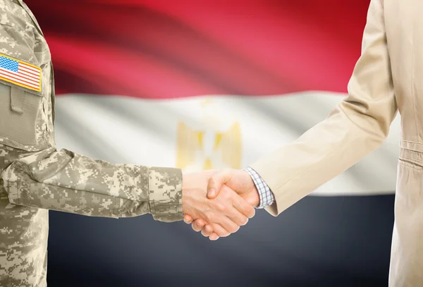 USA military man in uniform and civil man in suit shaking hands with national flag on background - Egypt — Foto Stock