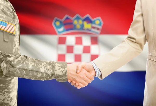 USA military man in uniform and civil man in suit shaking hands with national flag on background - Croatia — 图库照片