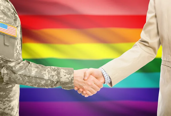 USA military man in uniform and civil man in suit shaking hands with national flag on background - LGBT people — стокове фото