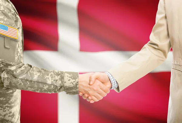 USA military man in uniform and civil man in suit shaking hands with national flag on background - Denmark — Zdjęcie stockowe