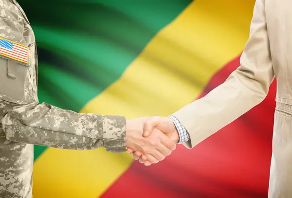 USA military man in uniform and civil man in suit shaking hands with national flag on background - Congo-Brazzaville — Stockfoto