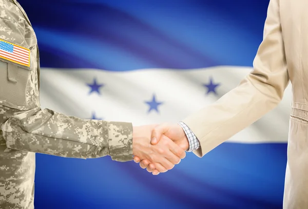 USA military man in uniform and civil man in suit shaking hands with national flag on background - Honduras — Stock Photo, Image