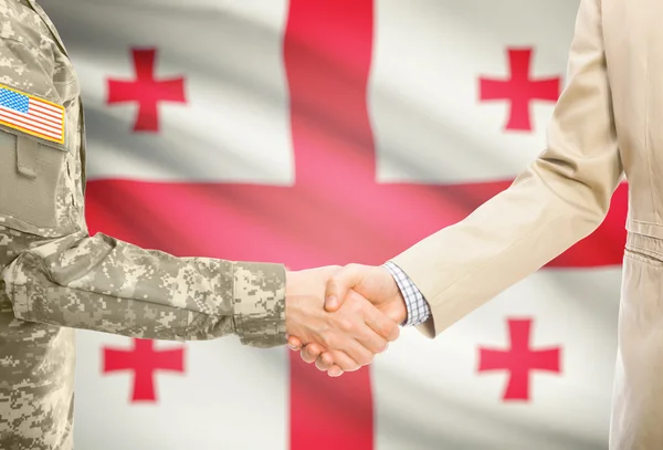 USA military man in uniform and civil man in suit shaking hands with national flag on background - Georgia — Foto de Stock