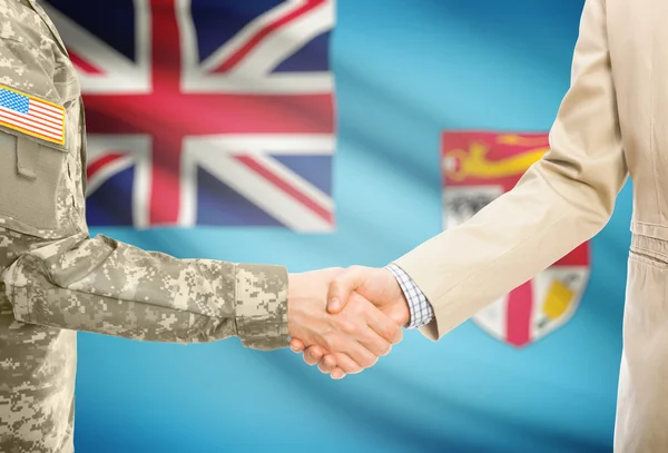 USA military man in uniform and civil man in suit shaking hands with national flag on background - Fiji — Stockfoto