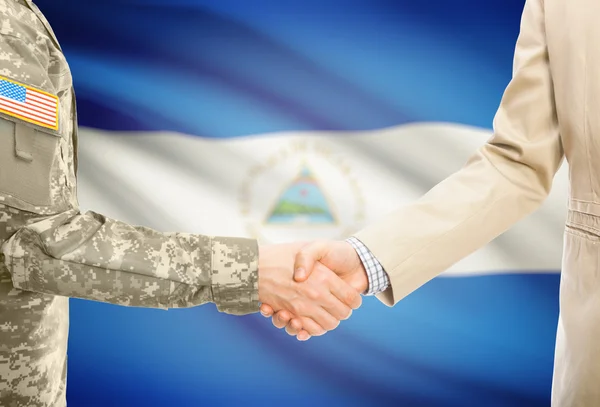США военный человек в военной форме и гражданской мужчина в костюме, рукопожатие с национальным флагом на фоне - Никарагуа — стоковое фото
