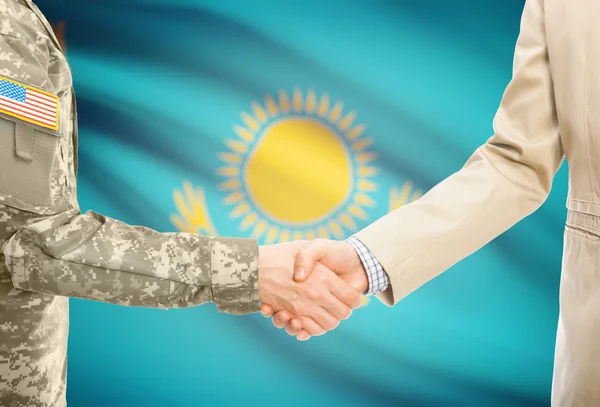 USA military man in uniform and civil man in suit shaking hands with national flag on background - Kazakhstan — Stock Photo, Image