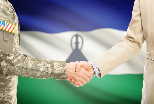 USA military man in uniform and civil man in suit shaking hands with national flag on background - Lesotho — Stock fotografie
