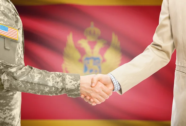 USA military man in uniform and civil man in suit shaking hands with national flag on background - Montenegro — Stockfoto
