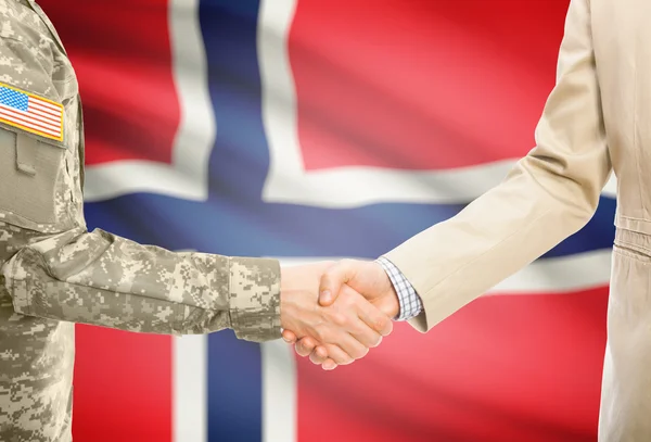 USA military man in uniform and civil man in suit shaking hands with national flag on background - Norway — 图库照片