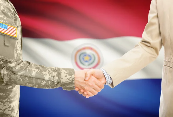 USA military man in uniform and civil man in suit shaking hands with national flag on background - Paraguay — Stockfoto