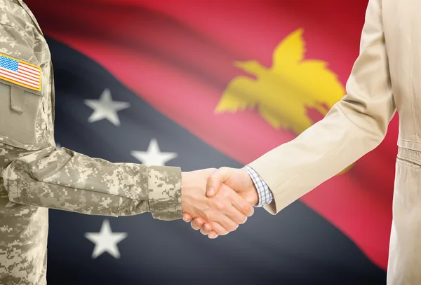 USA military man in uniform and civil man in suit shaking hands with national flag on background - Papua New Guinea — Stockfoto