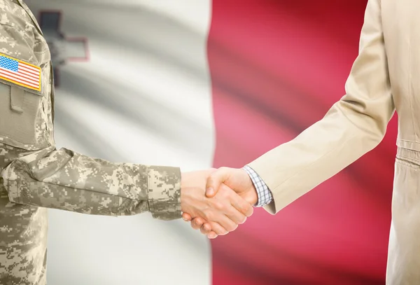 USA military man in uniform and civil man in suit shaking hands with national flag on background - Malta — 스톡 사진