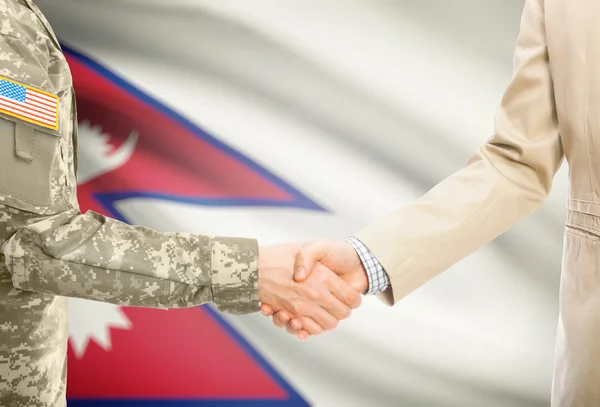 USA military man in uniform and civil man in suit shaking hands with national flag on background - Nepal — Stockfoto