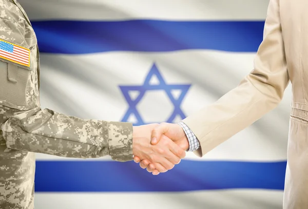 USA military man in uniform and civil man in suit shaking hands with national flag on background - Israel — Zdjęcie stockowe