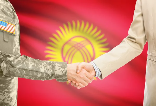 США военный человек в военной форме и гражданской мужчина в костюме, рукопожатие с национальным флагом на фоне - Кыргызстан — стоковое фото