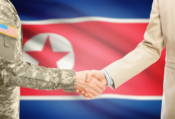 USA military man in uniform and civil man in suit shaking hands with national flag on background - North Korea — Stock Photo, Image