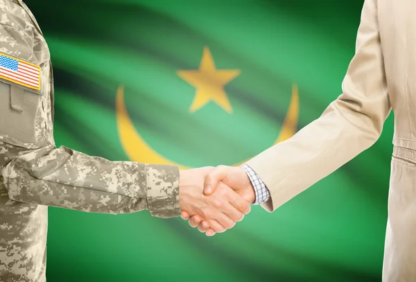 USA military man in uniform and civil man in suit shaking hands with national flag on background - Mauritania — ストック写真