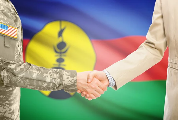 USA military man in uniform and civil man in suit shaking hands with national flag on background - New Caledonia — Stockfoto