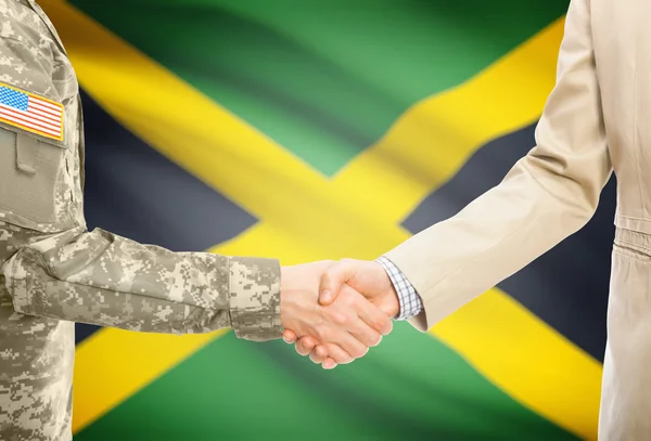 USA military man in uniform and civil man in suit shaking hands with national flag on background - Jamaica — Stock fotografie