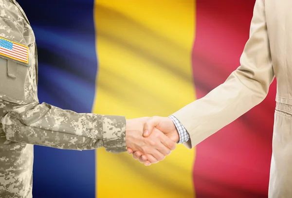 USA military man in uniform and civil man in suit shaking hands with national flag on background - Romania — Zdjęcie stockowe