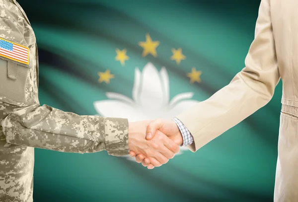 USA military man in uniform and civil man in suit shaking hands with national flag on background - Macau — Stock Fotó