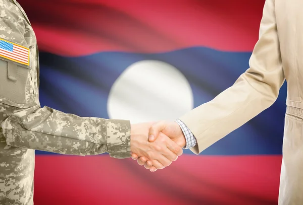 USA military man in uniform and civil man in suit shaking hands with national flag on background - Laos —  Fotos de Stock