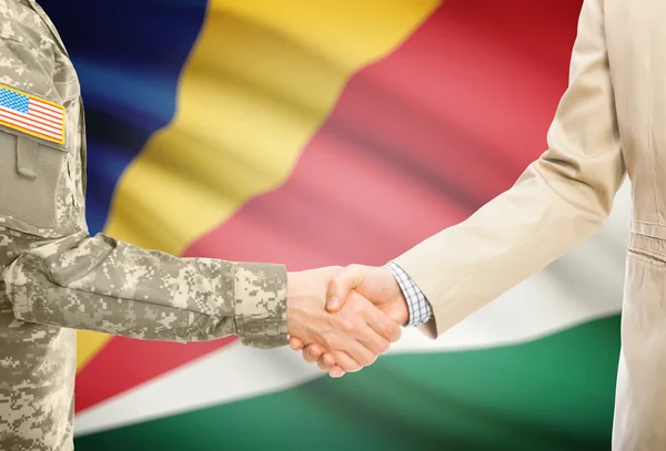 США военный человек в военной форме и гражданской мужчина в костюме, рукопожатие с национальным флагом на фоне - Сейшельские острова — стоковое фото