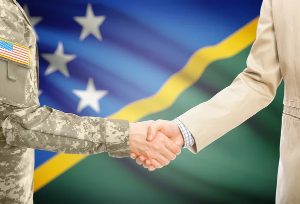 США военный человек в военной форме и гражданской мужчина в костюме, рукопожатие с национальным флагом на фоне - Соломоновы острова — стоковое фото