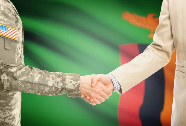 USA military man in uniform and civil man in suit shaking hands with national flag on background - Zambia — Stock Photo, Image