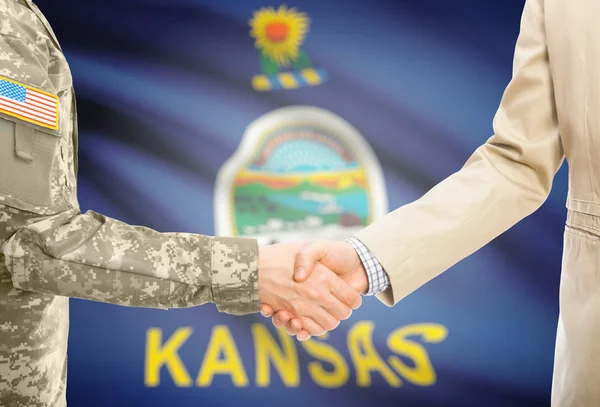USA military man in uniform and civil man in suit shaking hands with USA state flag on background - Kansas — Stock Photo, Image