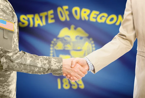 Usa militaire en uniforme et l'homme en costume civil serrant la main avec Usa drapeau d'état sur fond - Oregon — Photo