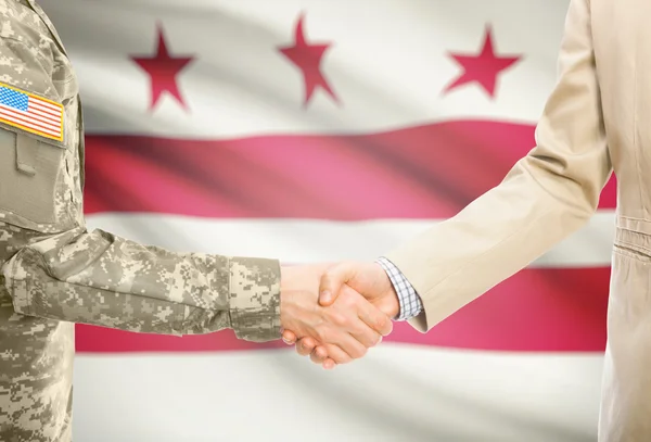 Usa militaire en uniforme et l'homme en costume civil serrant la main avec Usa drapeau d'état sur fond - District de Columbia — Photo