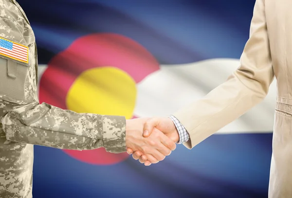 USA military man in uniform and civil man in suit shaking hands with USA state flag on background - Colorado — Stockfoto