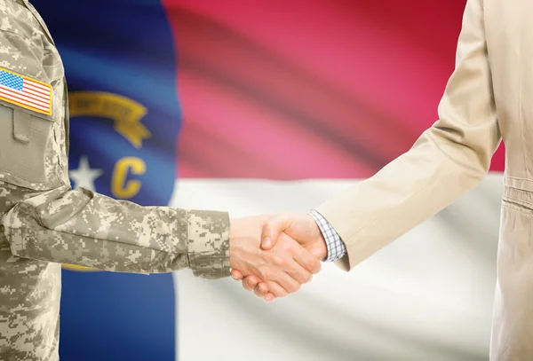 USA military man in uniform and civil man in suit shaking hands with USA state flag on background - North Carolina — Fotografia de Stock