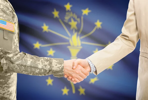 USA military man in uniform and civil man in suit shaking hands with USA state flag on background - Indiana