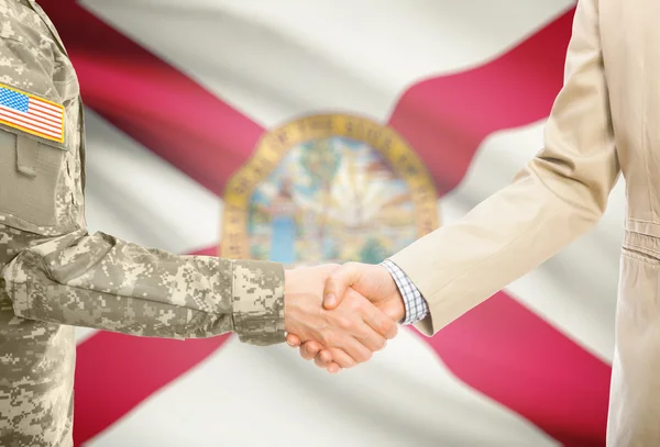 USA military man in uniform and civil man in suit shaking hands with USA state flag on background - Florida — Stock Photo, Image