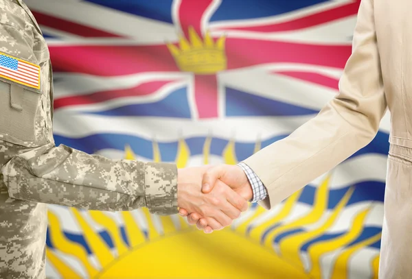 Vereinigte Staaten militärische Mann in uniform und Zivil Mann in Anzug Hände schütteln mit kanadischen Provinz-Flag auf Hintergrund - British Columbia — Stockfoto