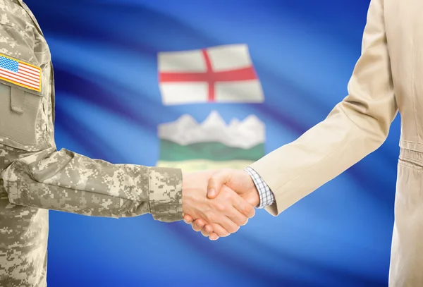 Hombre militar de usa en uniforme y civil hombre en traje sacudiendo las manos con la bandera de la provincia canadiense en el fondo - Alberta — Foto de Stock