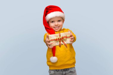 Noel Baba şapkalı şirin bir çocuk elinde hediyeli şirin bir zanaat gemisi tutuyor..